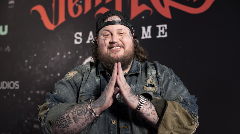 Jelly Roll smiling with hands in prayer form