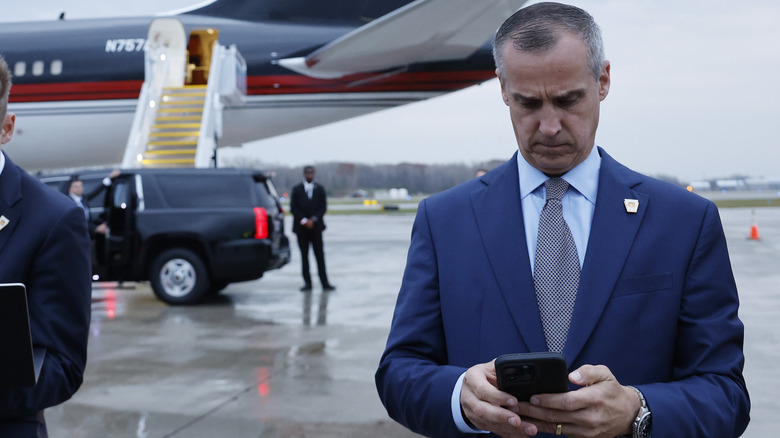 Corey Lewandowski using his phone on a tarmac