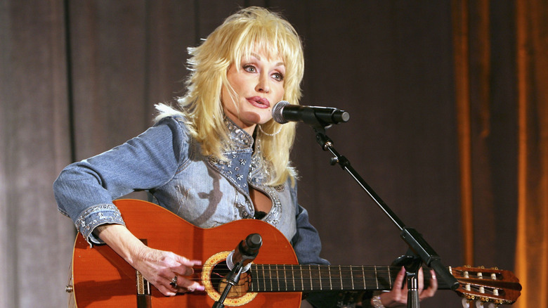 Dolly Parton on stage singling and playing the guitar