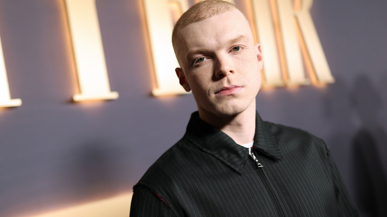 Cameron Monaghan buzz cut black zip up posing