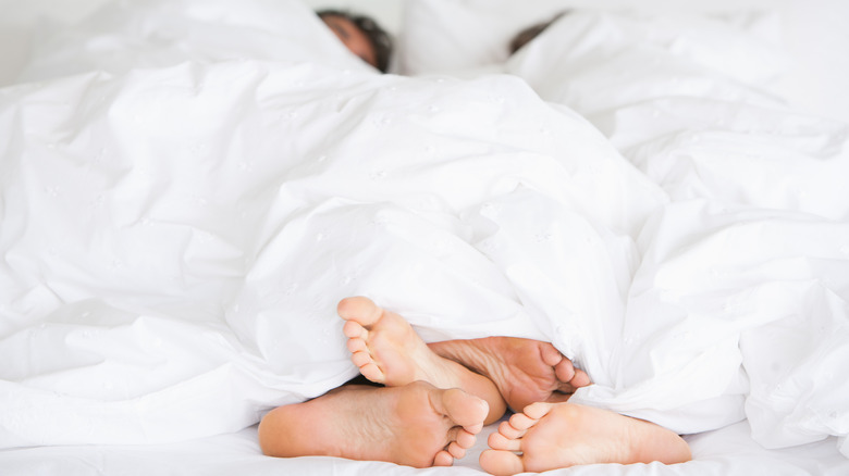 Two people in bed with feet intertwined