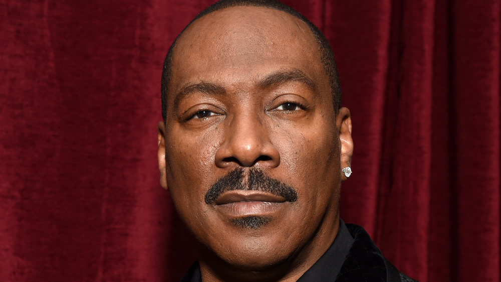 Eddie Murphy poses in front of a red curtain in 2019