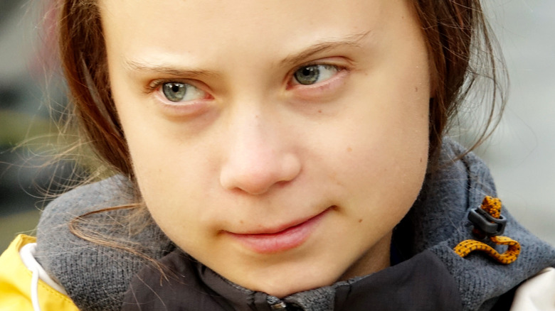 Greta Thunberg poses in a yellow winter jacket. 