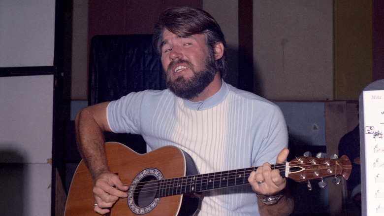 Young Kenny Rogers playing a guitar.