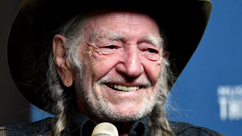 Willie Nelson smiles in a hat.