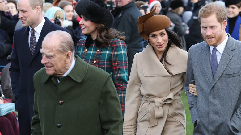Prince Harry and Meghan Markle walking behind Prince Philip