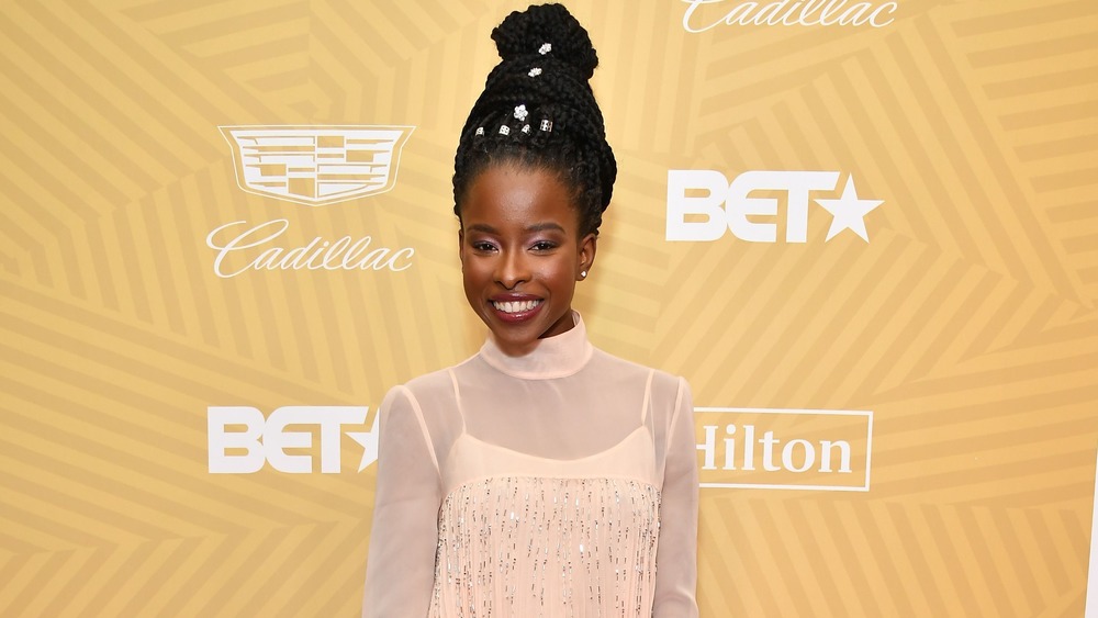 Amanda Gorman with her hair in an updo smiles on the red carpet