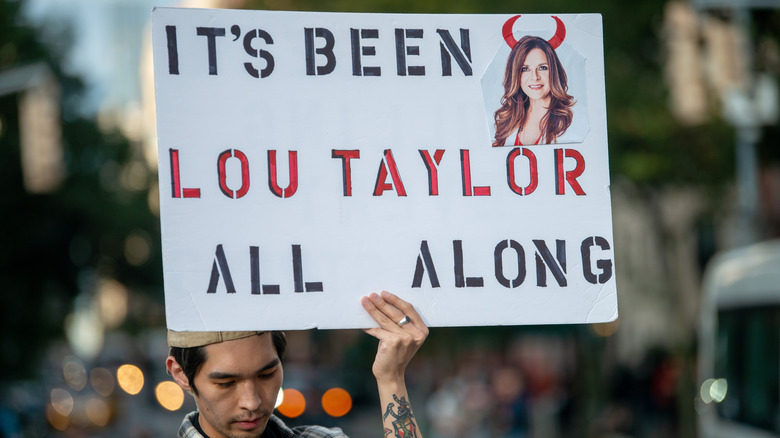 Protester holds sign against Lou Taylor