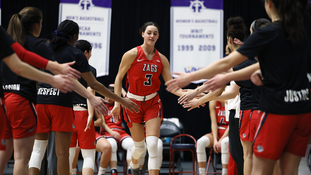 Jenn Wirth smiles as she gives high-fives to her teammates on the court