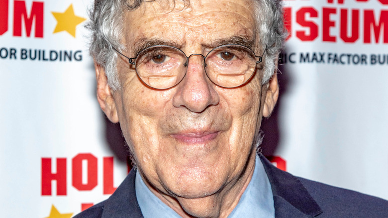 Elliott Gould smirking on red carpet at an event 