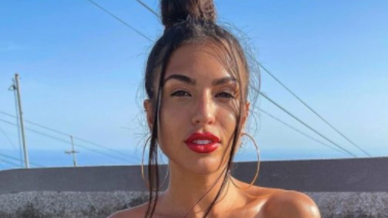 Emily Faye Miller wearing red lipstick and hoop earings with slight smile