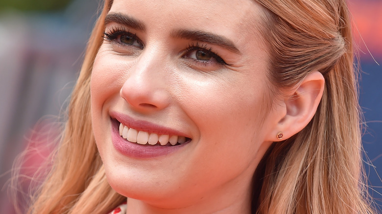 Emma Roberts smiles with side hair strand pulled back