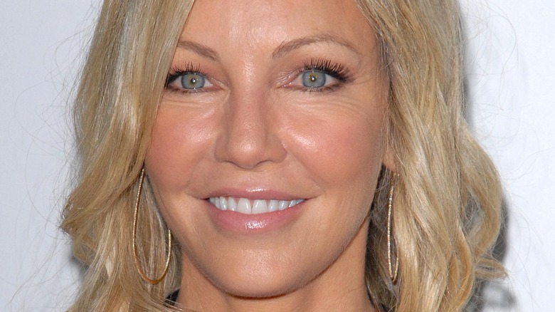 Heather Locklear smiles while wearing large teardrop earrings 