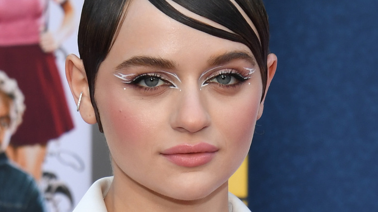 Joey King wears white eye makeup and a white blazer