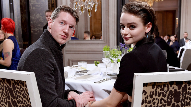 Steven Piet and Joey King sit and hold hands at an event