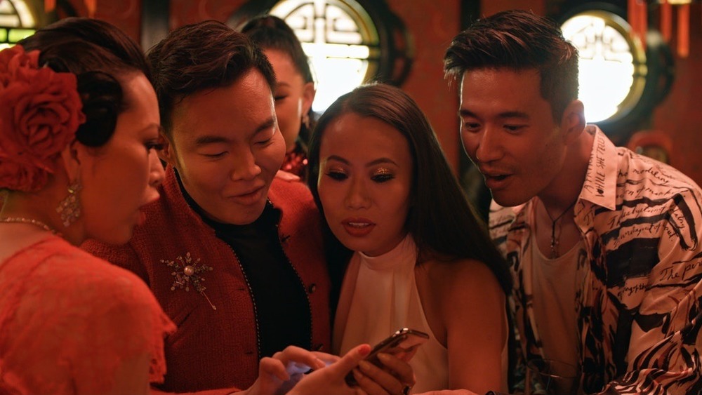 The cast of Netflix's Bling Empire looking at a phone on set