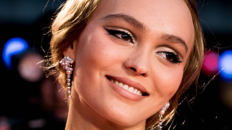 Lily-Rose Depp smiling in drop earrings