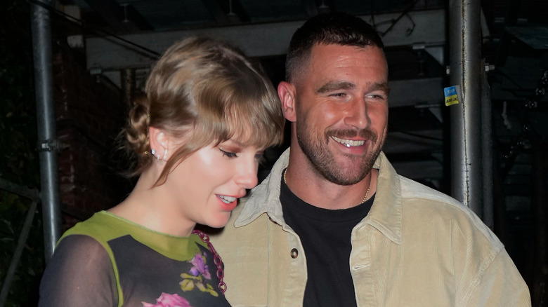 Taylor Swift and Travis Kelce holding hands and smiling