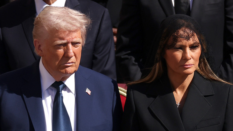 Donald Trump staring forward solemnly while Melania Trump frowns