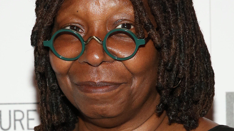 Whoopi Goldberg smiling in green glasses