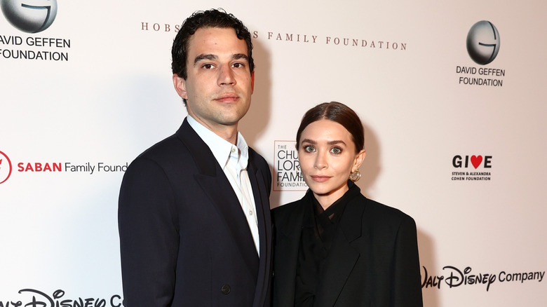 Louis Eisner and Ashley Olsen posing red carpet black suits