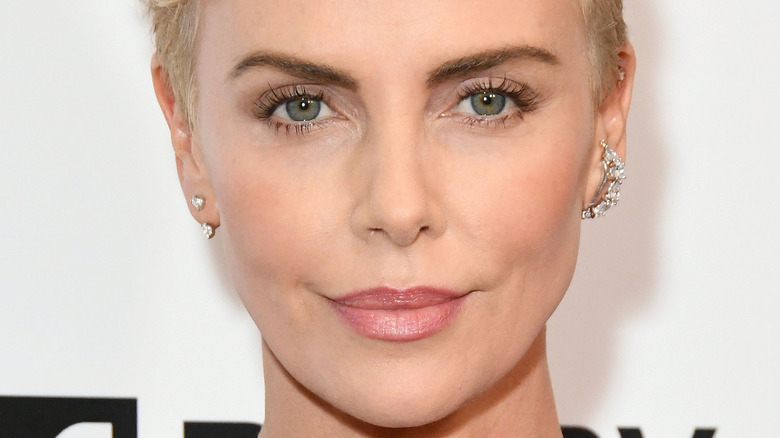 Charlize Theron with diamond earrings against a white backdrop