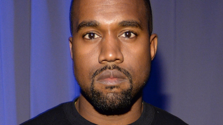 Kanye West poses in a black sweatshirt.