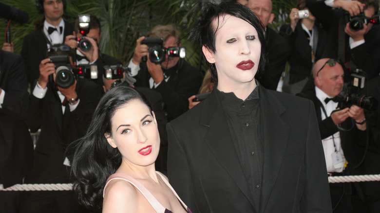 Dita Von Teese and Marilyn Manson pose in front of photographers