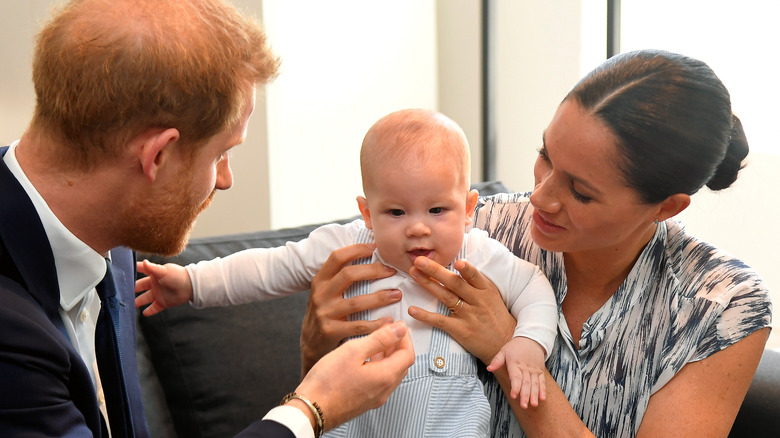 Prince Harry, Meghan Markle, and Prince Archie sitting on a couch