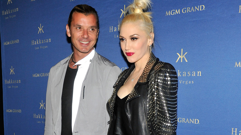 Gavin Rossdale smiling and wearing a grey jacket, and Gwen Stefani in black leather jacket with a neutral expression, posing together