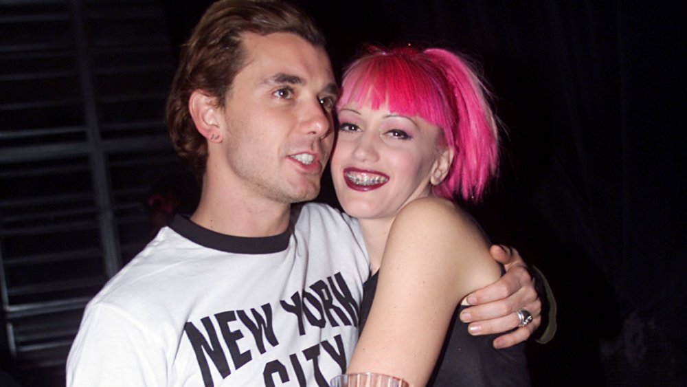 Gavin Rossdale in a white-and-black t-shirt, hugging a pink-haired Gwen Stefani in the '90s