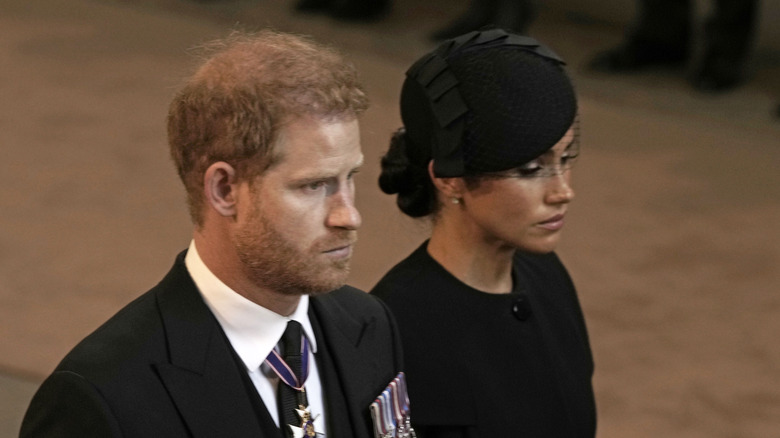 Prince Harry and Meghan Markle looking solemn