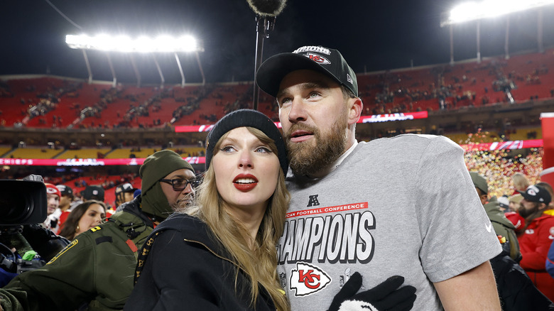 Taylor Swift and Travis Kelce embracing on the field at a Kansas City Chiefs game