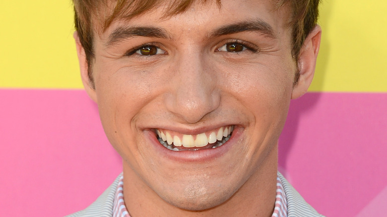 Lucas Cruishank smiling on the red carpet in a blue striped suit jacket