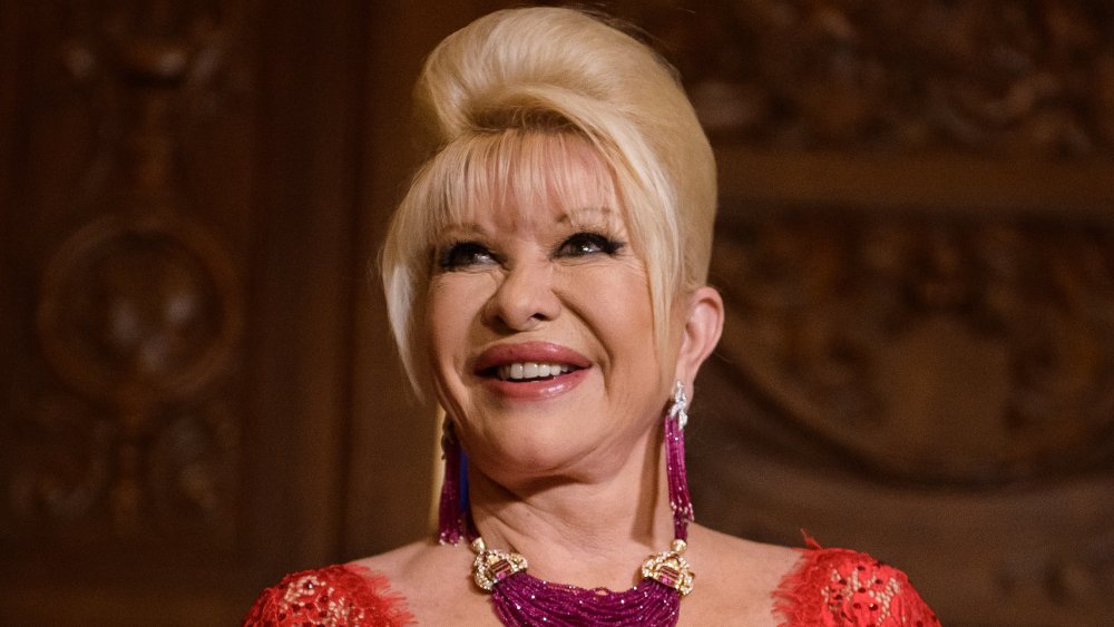 Ivana Trump in a red dress, smiling while looking up and to the side