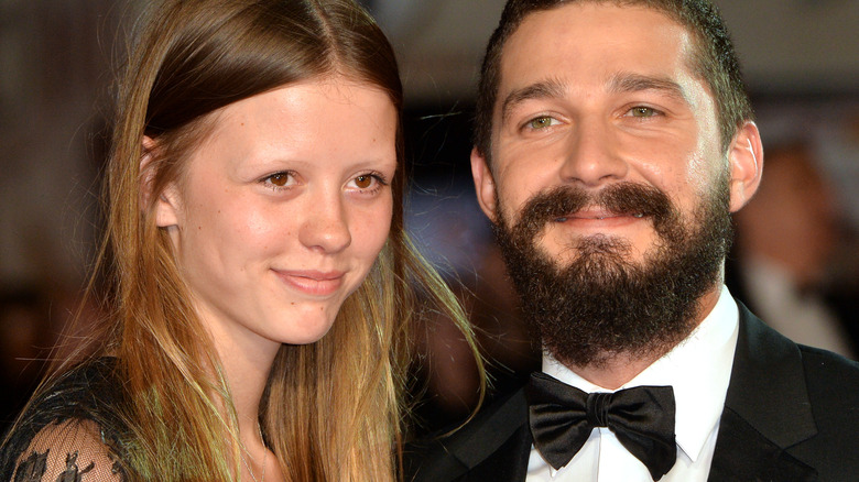 Mia Goth and Shia LaBeouf smile in black dress attire