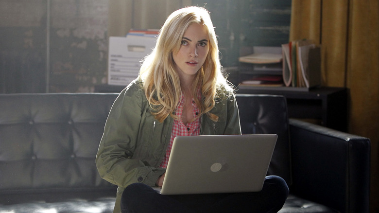 Emily Wickersham sitting with a laptop in a scene from NCIS