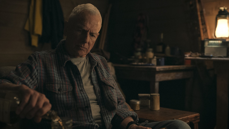 Mark Harmon pouring a drink and sitting on a chair in a scene from NCIS