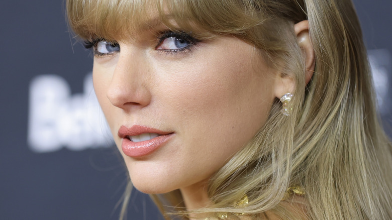Taylor Swift looking over her shoulder wearing diamond earrings