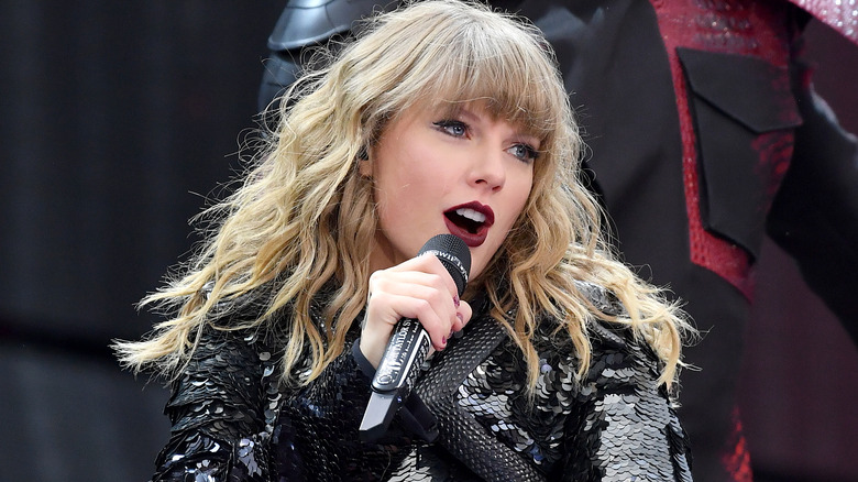 Taylor Swift singing into a microphone wearing black