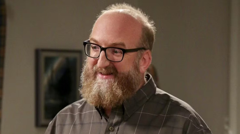 Bert wearing a plaid shirt and glasses and smiling on The Big Bang Theory