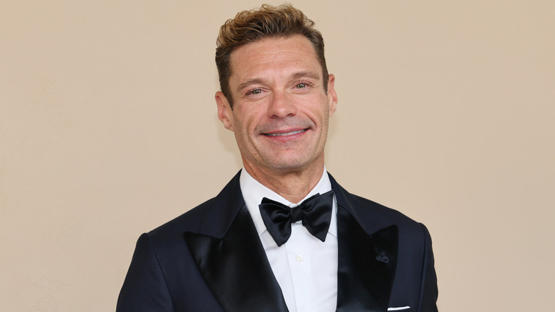 Ryan Seacrest smiling in a tuxedo.
