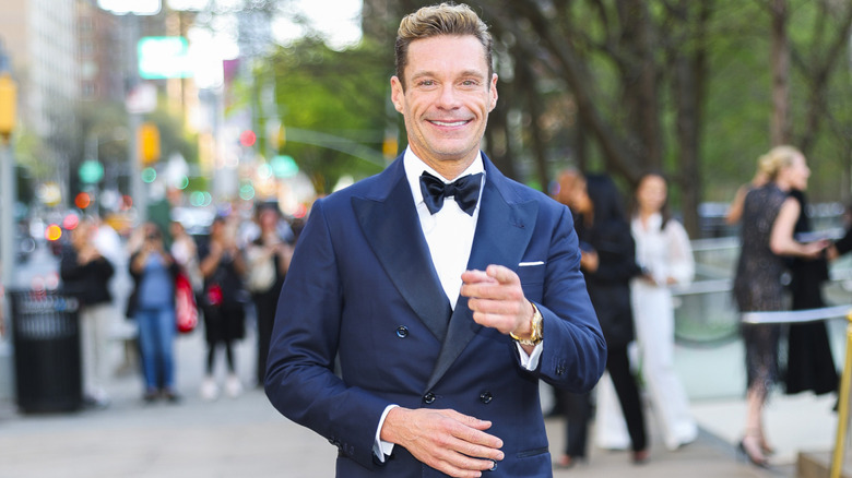 Ryan Seacrest smiling and pointing at the camera outdoors.