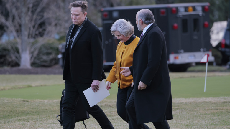 Elon Musk carrying Susie Wiles' bag to a waiting helicopter.