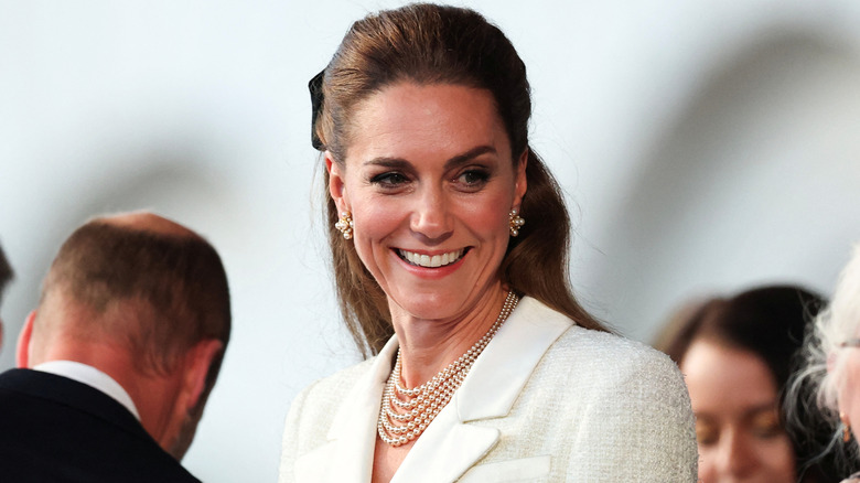 Kate Middleton smiling and wearing a white top