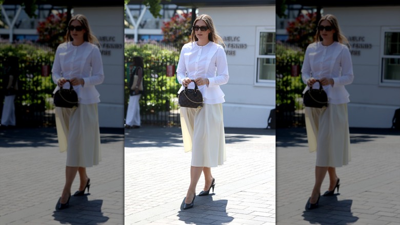 Maria Sharapova walking at Wimbledon holding purse in front of her.