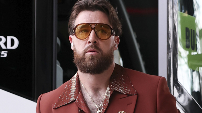 Travis Kelce arriving to the 2025 Super Bowl in rust-colored suit