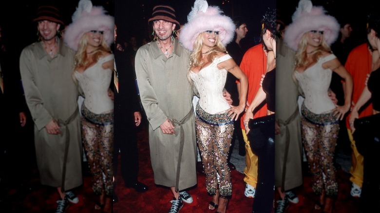 Pamela Anderson wearing a pink fluffy hat and white corset with Tommy Lee wearing a trenchcoat and hat.