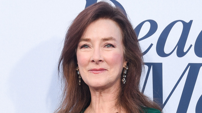 Valerie Mahaffey wearing a green dress and smiling over her shoulder
