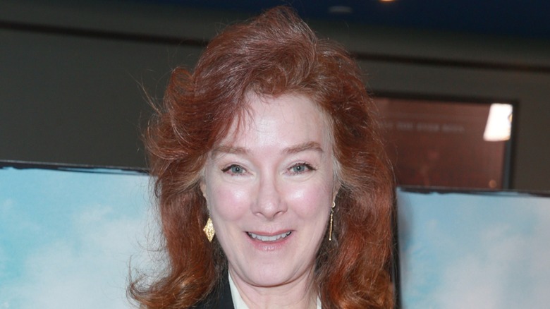 Valerie Mahaffey long red hair styled, smiling at the camera